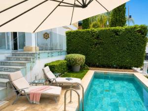 a swimming pool with two chairs and an umbrella at FINELINE Villa in Limassol