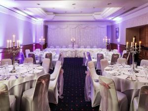 a room with tables and chairs in a room with purple walls at Mercure York Fairfield Manor Hotel in York