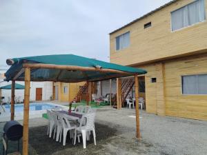 a table and chairs under a green umbrella next to a building at Cabañas Punta Negra in Punta Negra