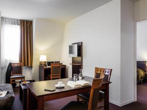 a hotel room with a table and chairs and a room at Aparthotel Adagio Access Paris Porte De Charenton in Charenton-le-Pont