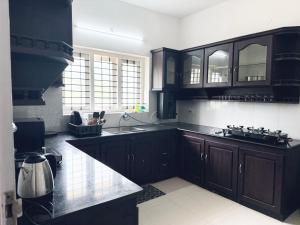 a kitchen with dark wood cabinets and a sink at Zenaura Casa Villa 2 in Cochin
