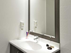 a bathroom sink with a mirror and a toothbrush at Aparthotel Adagio Access Toulouse St Cyprien in Toulouse