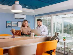 a man and woman sitting at a table with a laptop at Aparthotel Adagio Access Marseille Prado Périer in Marseille