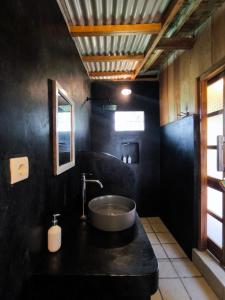 a black bathroom with a sink and a mirror at Tetebatu Sasak House Bungalow in Tetebatu