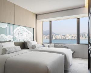 two white beds in a room with a large window at Hyatt Centric Victoria Harbour in Hong Kong