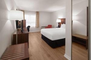a hotel room with a bed and a mirror at Ramada by Wyndham Arnprior in Arnprior +49 photos