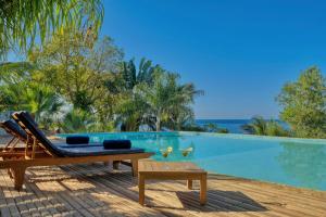 a pool with a lounge chair and a table with wine glasses at Manja Kely Lodge - Nosy Komba Island in Nosy Be