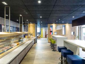 a restaurant with a counter and blue stools at ibis budget Zurich Airport in Glattbrugg