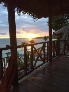 a view of the ocean from a porch with the sunset at Nini's Beach Bungalows in Bira