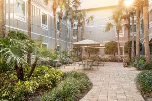 an outdoor patio with tables and chairs and palm trees at Hampton Inn New Smyrna Beach in New Smyrna Beach