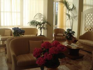 a living room with couches and a table with flowers at Hotel Arcade in Rimini