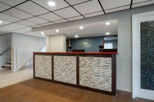 a lobby with a counter with a brick wall at Baymont by Wyndham Waukesha in Waukesha +36 photos