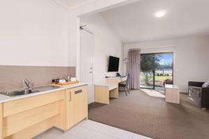 a kitchen with a sink and a living room at Quality Hotel Point Cook in Point Cook