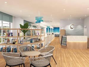 a library with chairs and a table and bookshelves at Comfort Hotel ERA Ishigaki Island in Ishigaki Island