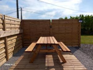 a wooden picnic table in front of a wooden fence at Maisonnette cosy proche de la côte in Lesneven