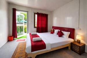 a bedroom with a large bed with red curtains at Snowpeak Retreat in Hundar