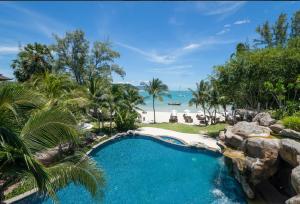 a resort pool with a view of the beach at Royal Muang Samui Villas - SHA Extra Plus in Choeng Mon Beach