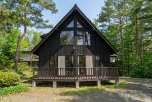 a small black house with a porch in the woods at Reposer Hakuba Hotel and Offsite Villa in Hakuba