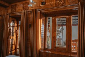 a room with windows in a wooden house at Jigyasa Homestay in Almora +22 photos