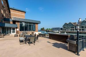 eine Terrasse mit Tischen, Stühlen und einem Grill in der Unterkunft The Harborview on Lake Michigan, an Ascend Collection Hotel in Port Washington