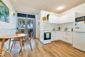 a kitchen with white appliances and a table and chairs at Beachfront Bliss Studio Apt on the Foreshore in Nightcliff