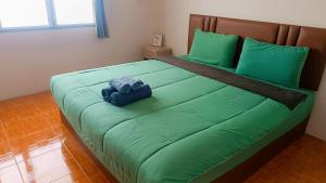 a large green bed with a blue towel on it at Pai Town Home in Pai