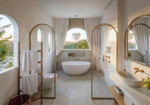a bathroom with a large tub and two sinks and a bath tub at Svara Boutique Residences in Uluwatu