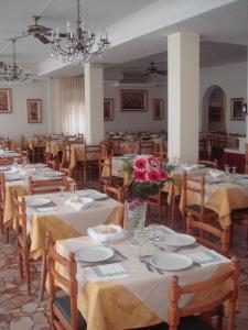 una sala da pranzo con tavoli e sedie con fiori di Hotel Arcade a Rimini