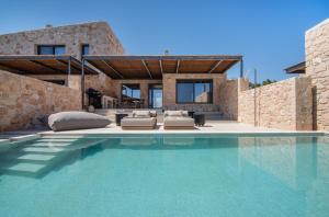 a villa with a swimming pool in front of a house at AÁSHNA Suites and Residences in Vaia