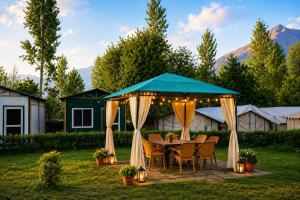 a table and chairs under a blue canopy in a yard at Snowpeak Retreat in Hundar