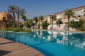a large swimming pool with palm trees and a building at The Westin Pushkar Resort & Spa in Pushkar