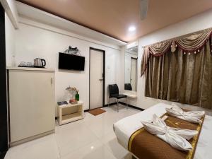 a hotel room with a bed and a television at New Vyankatesh in Mahabaleshwar