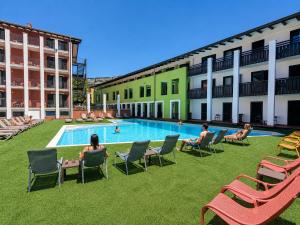 a group of people sitting in chairs by a swimming pool at Hotel Vela in Nago-Torbole