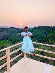 a young girl in a blue dress standing on a fence at Keyangjhiri Eco Resort, Lama, Bandarban in Bāndarban +2 photos