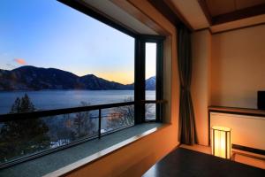 a room with a large window with a view of a lake at Yutorelo Nikko in Nikko