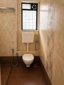 a bathroom with a toilet and a window at Sk Holiday Apartment in Alibaug