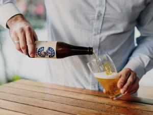 a man pouring a bottle of beer into a glass at Novotel Newcastle Beach in Newcastle