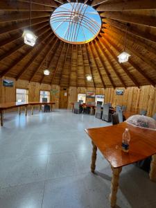 a large room with a wooden ceiling with tables and a window at Bosogo Yurt camp in Bokonbayevo