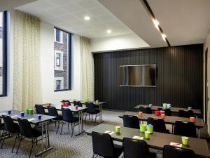 a conference room with tables and chairs and a screen at ibis Adelaide in Adelaide