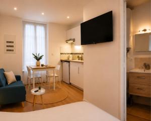 a living room with a couch and a tv on a wall at Les Escales de Choisy in Choisy-le-Roi