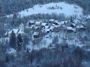 a village covered in snow with trees and houses at Kuća za odmor Lešnica in Brod na Kupi