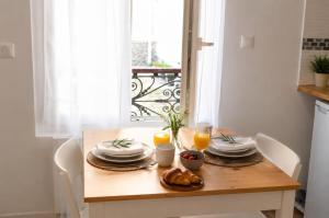a wooden table with plates of food and orange juice at Les Escales de Choisy in Choisy-le-Roi +3 photos