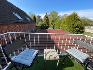 two chairs and a bench on a balcony at Weener - City Apartment mit Garten in Weener