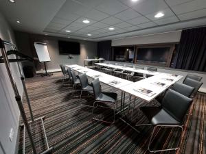 a conference room with tables and chairs and a projection screen at ibis Styles Caen centre gare in Caen