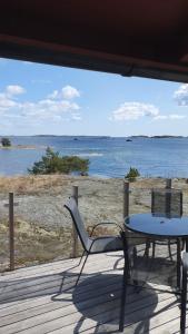 a table and chair on a deck with a view of the ocean at Lillstugan at Sävö in Västerljung