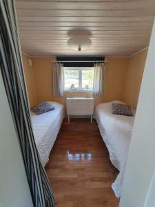 two beds in a small room with a window at Lillstugan at Sävö in Västerljung