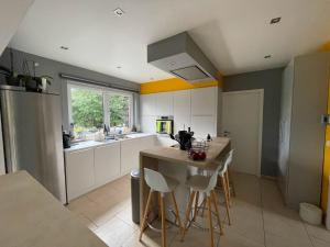 a kitchen with white cabinets and a kitchen island with stools at Maison avec piscine à Dinant in Sorinnes