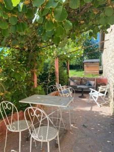 a patio with a table and chairs under a tree at Manoir La Buissonnière in Plescop +2 photos