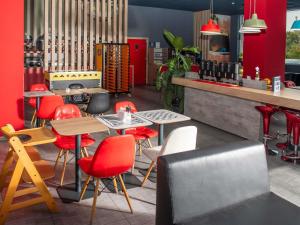 a restaurant with red chairs and tables and a counter at Ibis Sofia Airport Hotel in Sofia