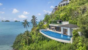 a house on a hill next to the ocean at Conrad Koh Samui in Taling Ngam Beach